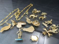 Sixteen gold coloured metal charms some with foreign marks and a gold coloured chain.