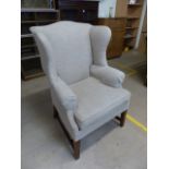 Antique beige upholstered wing back fire side armchair with mahogany legs
