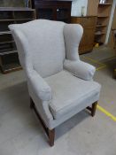 Antique beige upholstered wing back fire side armchair with mahogany legs