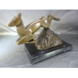 Art Deco bronze deer of angular form leaping over a rock. On a black slate plinth with built in