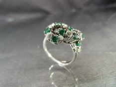 18ct White Gold ring (1993) set with Emeralds and Diamonds, in the form of a lovers knot. 12