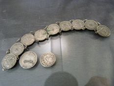 A white metal bracelet set with 9 three pence coins. The earliest 1931, with additional three