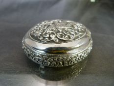 Indian White coloured metal pill/trinket box of ovular form. Decorated in relief with floral