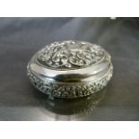 Indian White coloured metal pill/trinket box of ovular form. Decorated in relief with floral