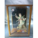 Oriental figure in upholstery inside a modern three sided glass case.