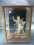 Oriental figure in upholstery inside a modern three sided glass case.