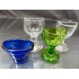 Victorian glass eye baths. Two clear glass, one green and the other Bristol Blue colour but marked