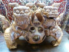 Pair of Foo dogs carved in wood. One with a ball in the mouth and both with a paw on a wooden ball