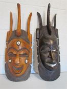 Two carved hardwood african fertility masks,one dark stained and the other inlaid with cowrie