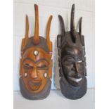 Two carved hardwood african fertility masks,one dark stained and the other inlaid with cowrie