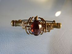 A brass nanny brooch with scroll mount and set with an Amethyst, screw thread and needle