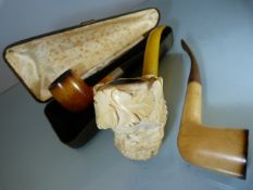 Meerschaum pipes, one cased. One carved with large head and amber stem and one other (3)