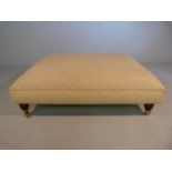 Large low upholstered footstool on brass castors