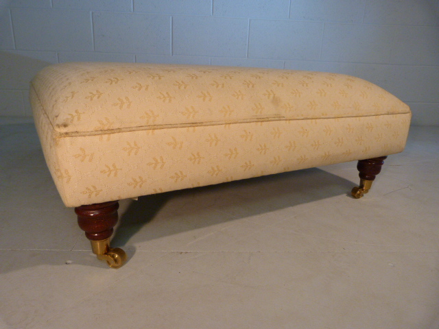 Large low upholstered footstool on brass castors - Image 2 of 5