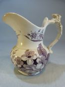 Creamware milk jug in purple transfer with scrolling handle.