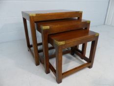 Nest of mahogany tables in the campaign style with fitted brass corners and central plaque