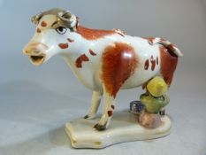 Pottery cow creamer 19th Century - the cow red and white with a poly-chrome decorated milkmaid
