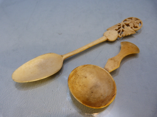 Antique carved medicine spoon and one other with long stem leading to a floral pierced top.