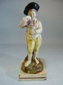 Staffordshire pearlware figure of a young boy wearing top hat, holding grapes above a vessel