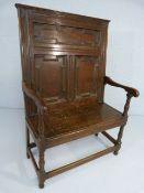 Oak single seater Antique settle with carved decoration to a tall back.