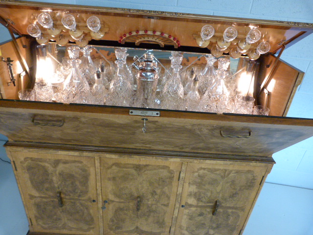 Art Deco walnut cocktail cabinet with drop front above two cupboards. Opens to reveal mirrored light