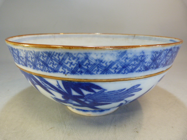 A Chinese bowl decorated in Blue and White with flowers and a two men in a sailing boat with a