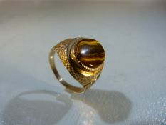 Gold coloured ring set with large Tigers eye stone. Gold metal unmarked.