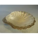 Hallmarked silver salt dish in the shape of a scallop with glass liner. Stamped 'Harrods' to back.
