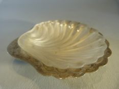 Hallmarked silver salt dish in the shape of a scallop with glass liner. Stamped 'Harrods' to back.