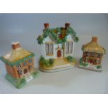 Three Victorian Staffordshire Pottery money boxes. c.1870 All modelled as cottages with greenery