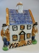 Staffordshire Prattware money type box c.1810 modelled as a house with two male figures either side.