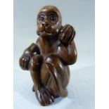 Japanese carved wood Netsuke - In the form of a seated monkey with glass eyes holding nuts, having a