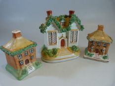 Three Victorian Staffordshire Pottery money boxes. c.1870 All modelled as cottages with greenery