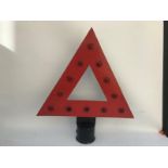 A triangular road warning sign with red glass reflectors.