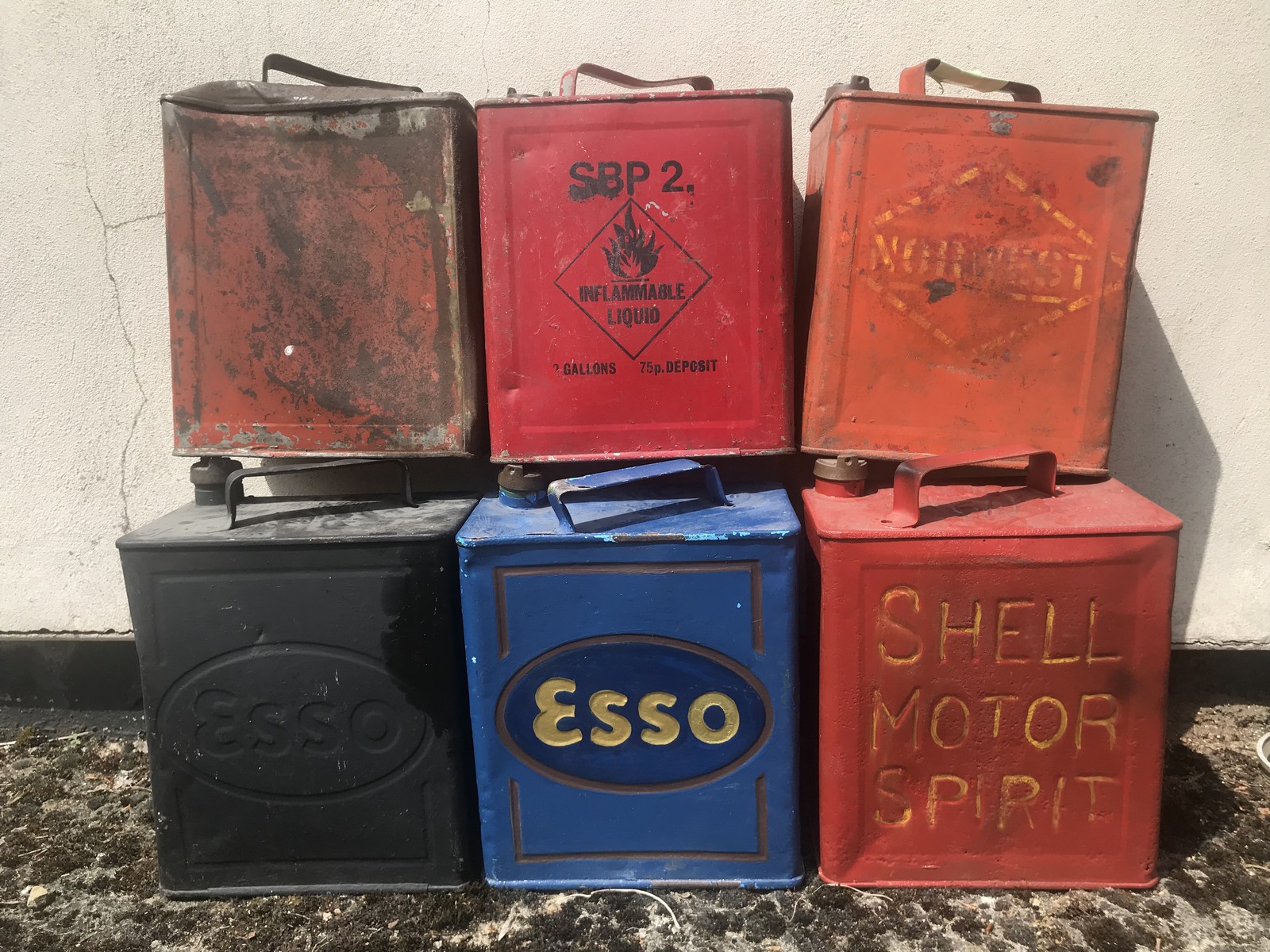 Six 2 gallon petrol cans including Esso and Shell.