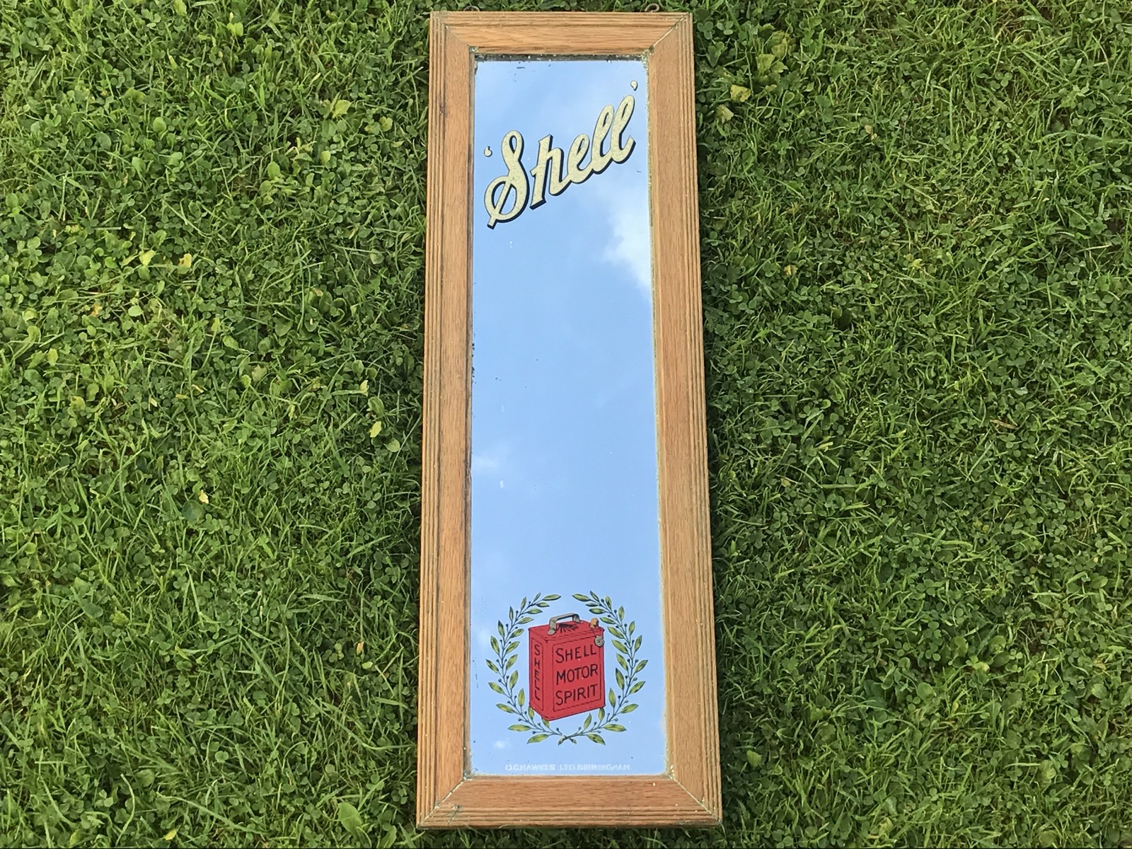 A Shell narrow advertising mirror with Shell Motor Spirit can within a laurel wreath motif, by O.