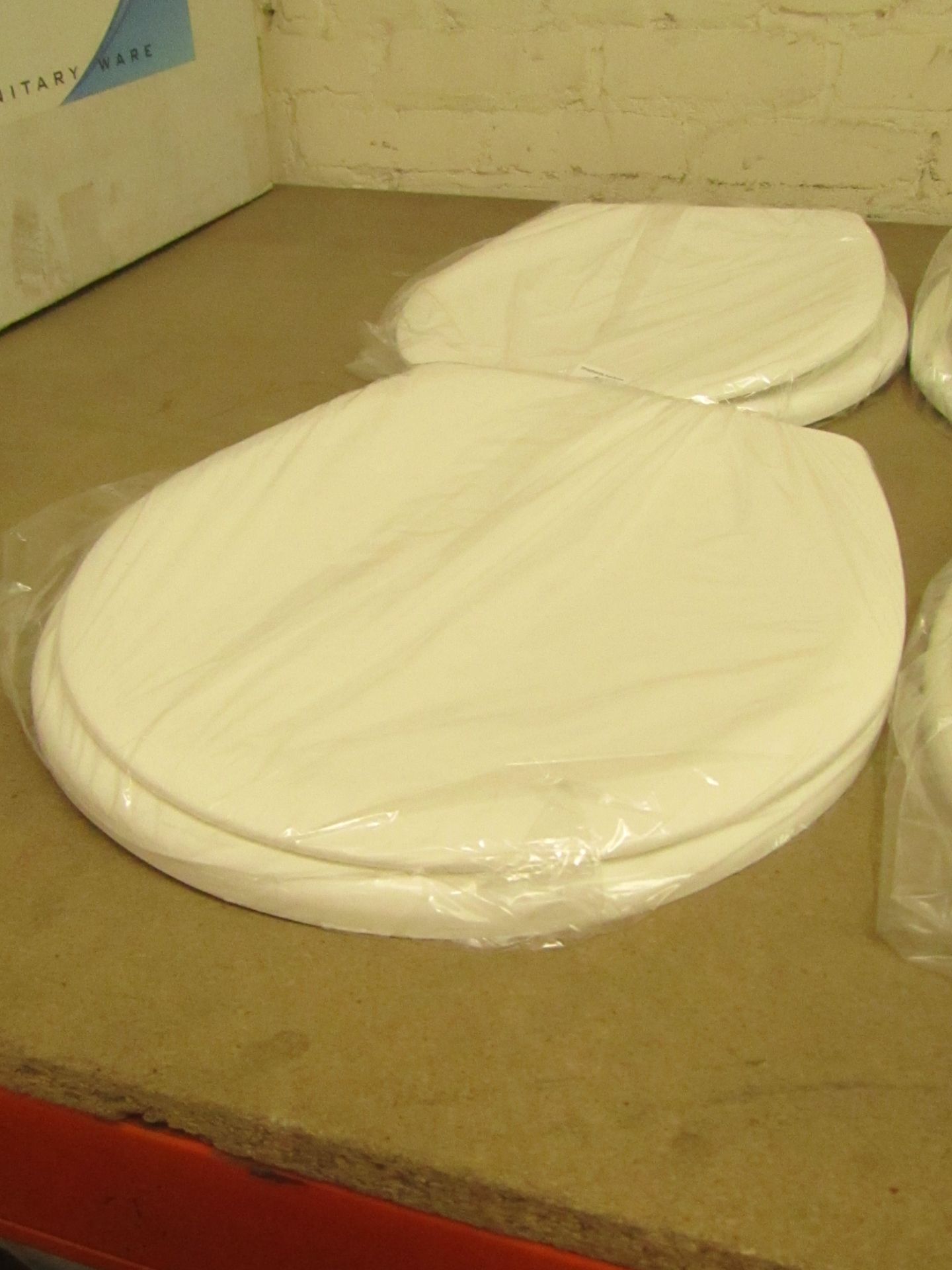 Cream coloured plastic toilet seat with fixings. New in packaging.