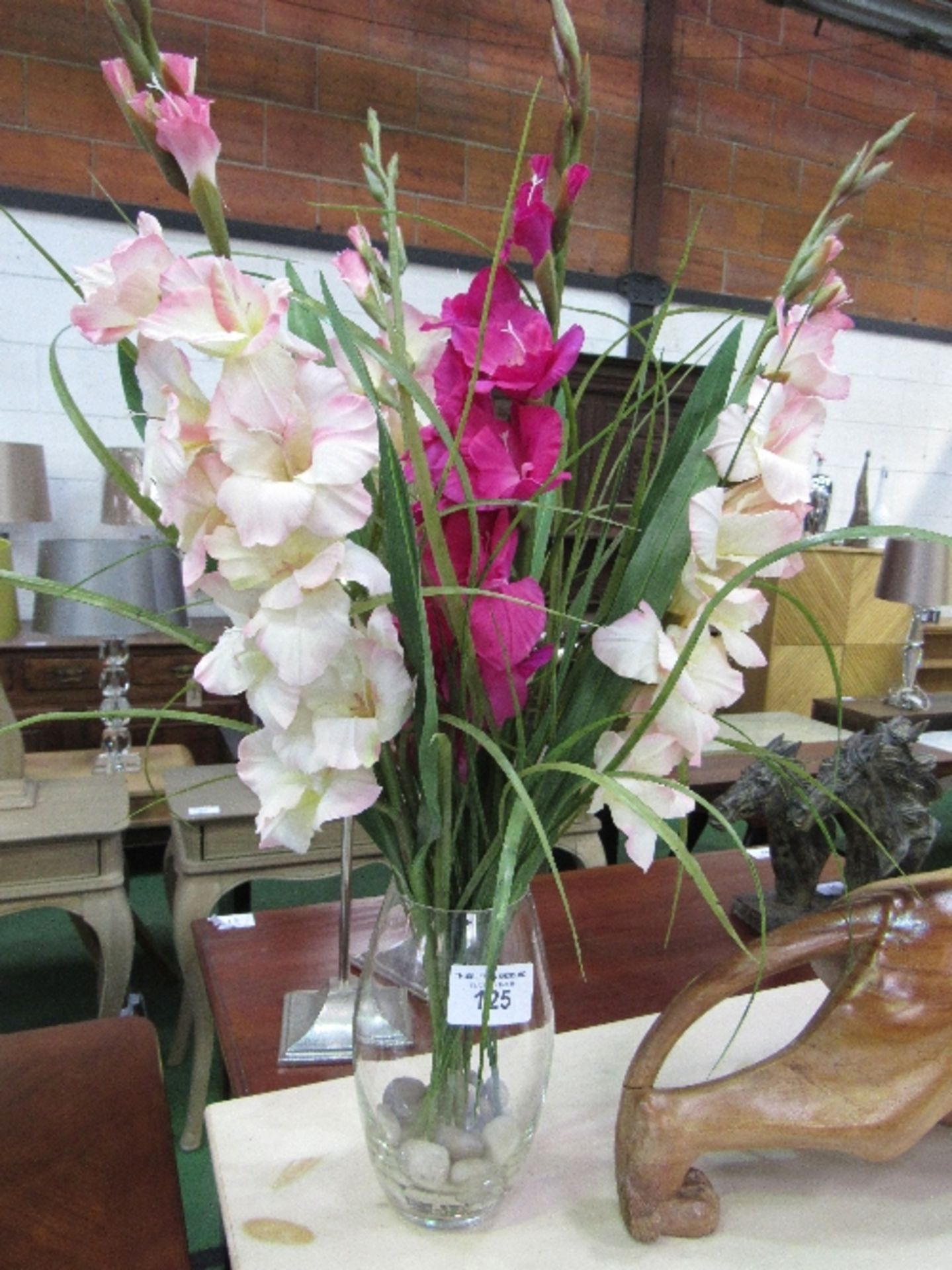 Artificial gladioli in glass vase