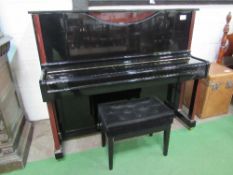 A Hemmington upright piano in gloss black finish with dark brown embellishments, on casters. Frame