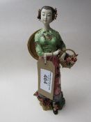 An oriental lady figurine with basket of flowers. Price guide £10-20.