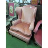 Large pink upholstered wing armchair. Price guide £50-60.
