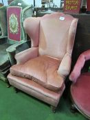 Large pink upholstered wing armchair. Price guide £50-60.