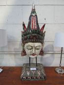 An Asian painted face mask on stand. Price guide £10-20.