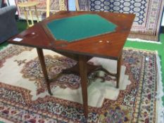 Edwardian mahogany envelope-type card table with display shelf, on casters, 78cms x 78cms x 71cms.