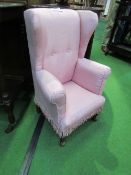 Pink upholstered child's wing back armchair. Price guide £20-30.