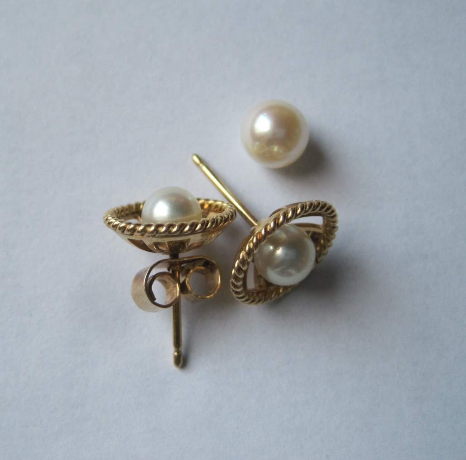 Pair of earrings decorated with a pearl nestled at the bottom of a circular gold [...]