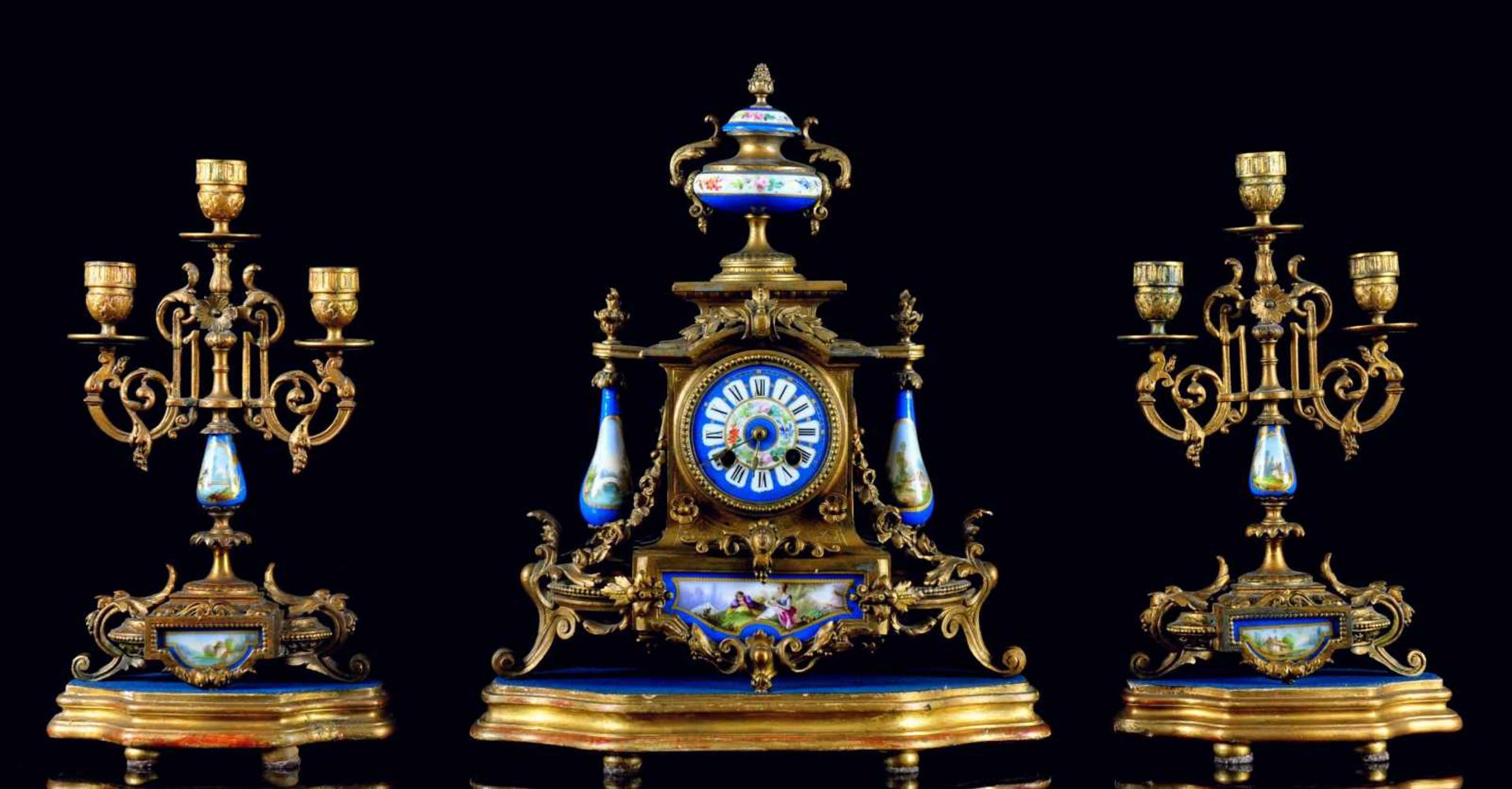 A GILT SPELTER AND SEVRES STYLE APPLIQUÉS CHIMNEY GARNITURE CONSISTING OF CLOCK, TWO CANDELABRAS AND