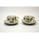 A pair of Meissen floral encrusted cups and saucers