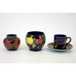 A group of three Moorcroft pieces including a wisteria vase, a pomegranate vase and a pansy