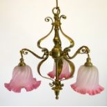 An Arts and Crafts brass pendant light fitting, with three pink opaque glass shades